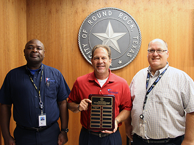 Gary Hudder (center) accepts the Hassan Farhat’s Safety and Risk Management Award for the Transportation Department from Kevin Vaughn (left) and Michael Bennett.