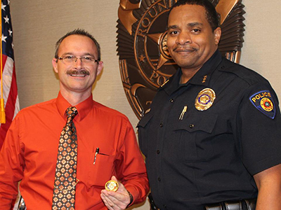 Detective John Combs (left) receives the Police Department's CHIP Challenge Coin from Chief Allen Banks